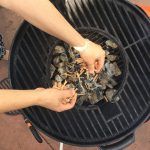 Adding the wood chips to the charcoal fire in our Stok kettle grill
