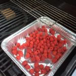 Raspberries on the grill with a wood chunk